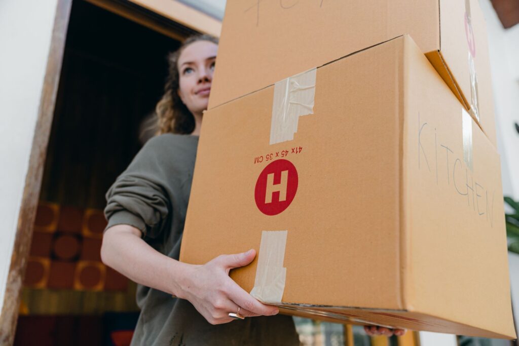 Young woman carrying cardboard boxes while moving out